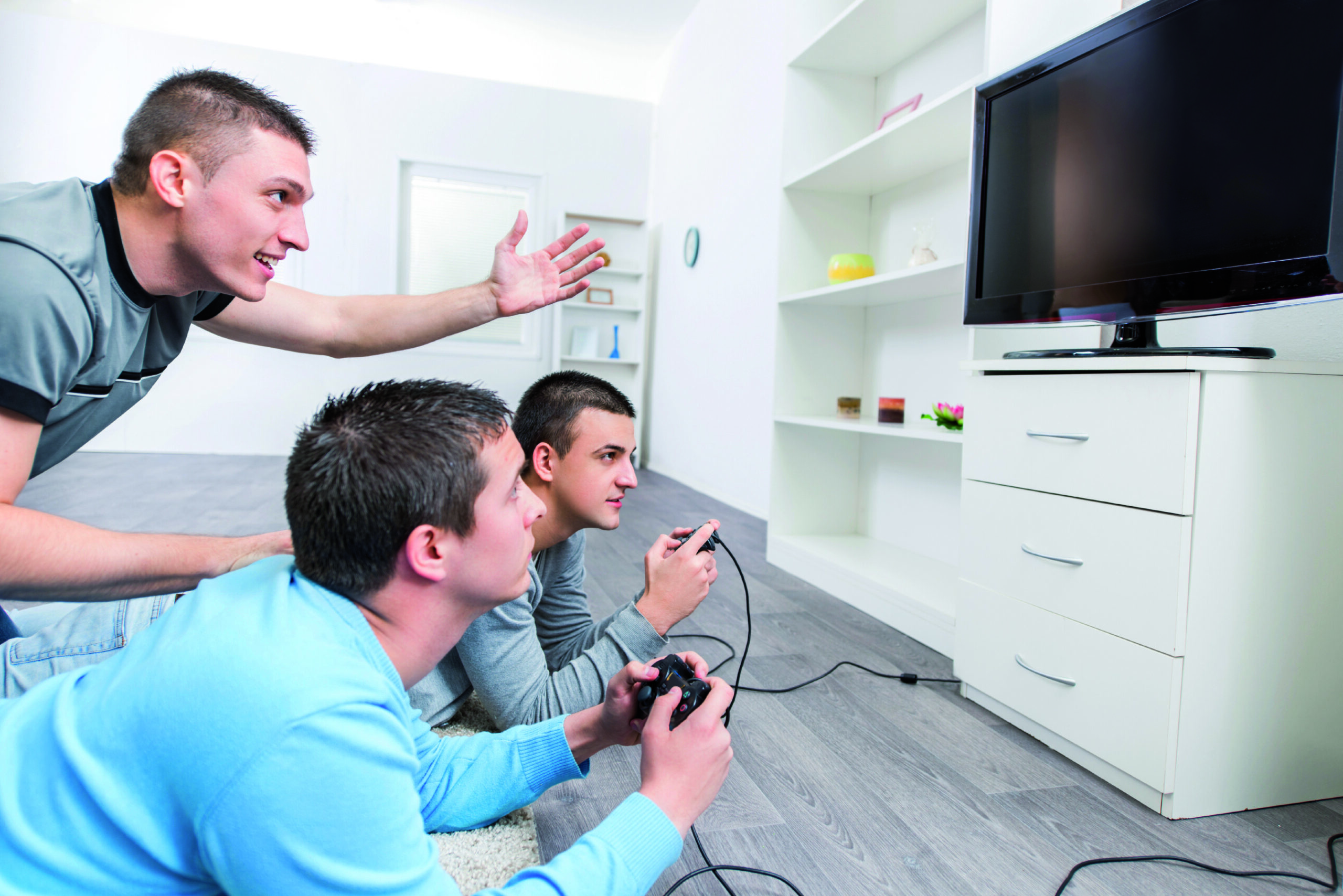Three male friends at home playing a video game.